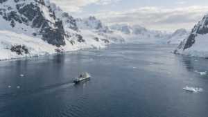 Expedition ship sailing between snowy Antarctic mountains